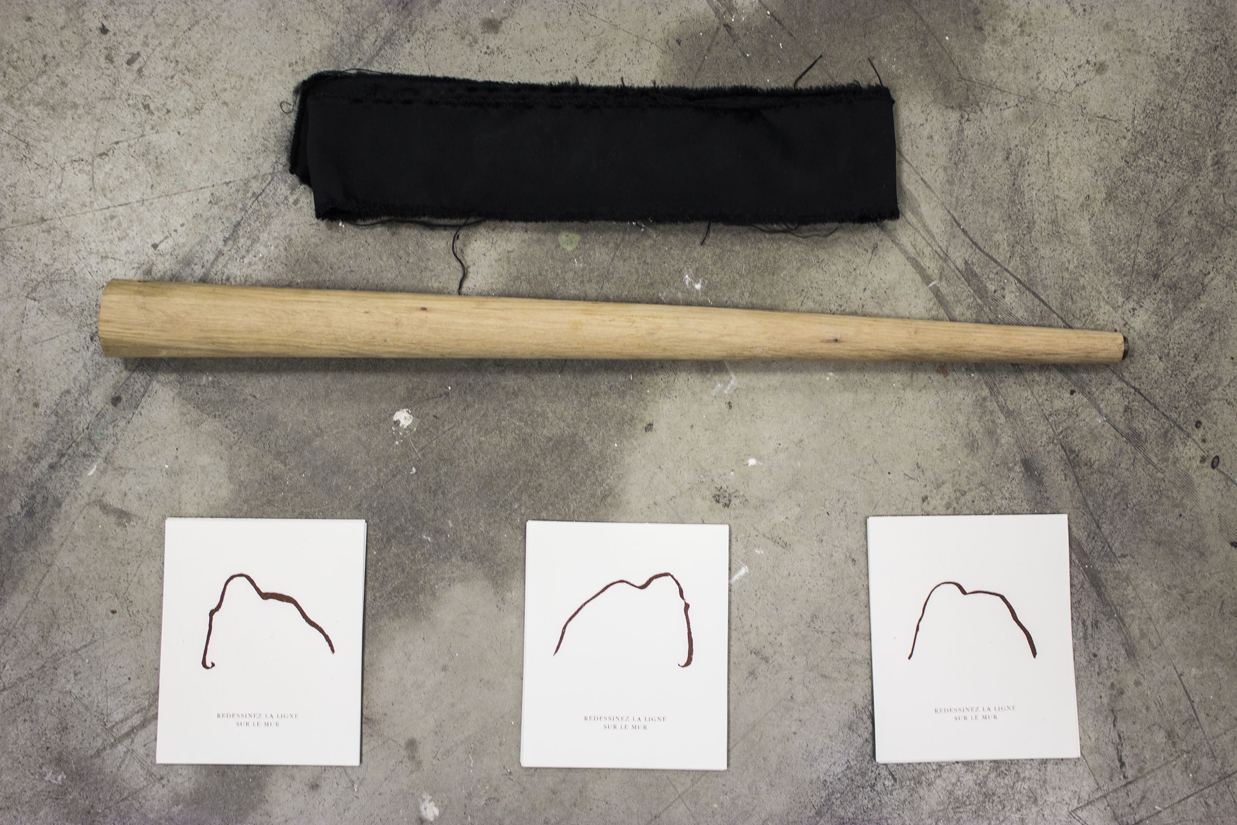 3 feuilles de dessins de lignes représentants des mammouth sont posées au sol à côté d'un pied de table devenue batte de baseball et d'un bandeau noir. on peut lire sur les feuilles : redessinez la ligne sur le mur.